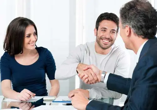 Conscape Lighting + Audio Three people sit at a desk, with two men shaking hands and a woman smiling, suggesting a business meeting or agreement—perhaps discussing outdoor lighting solutions in Toronto or GTA audio services.