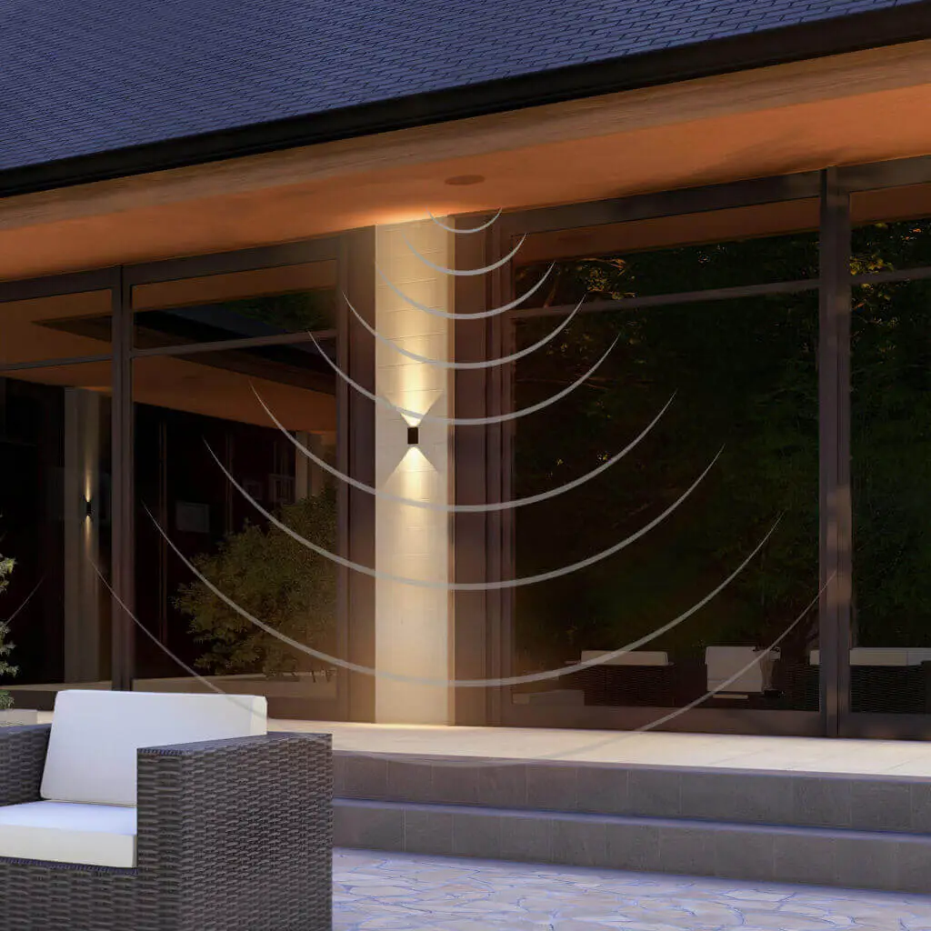 Conscape Lighting + Audio Modern outdoor wall light by GTA Lighting on a patio, casting overlapping semicircular light patterns on a pillar, with glass doors and wicker patio furniture visible.